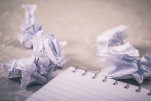 Notepad surrounded by crumpled up discarded drafts.